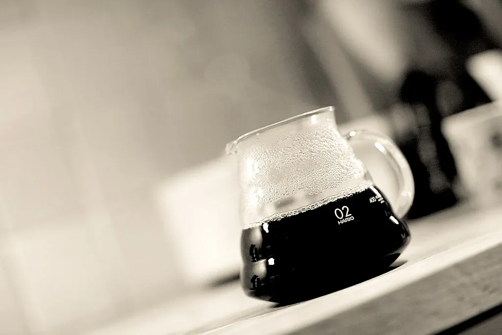 Glaskanna med kaffe, handtag och graderade markeringar.