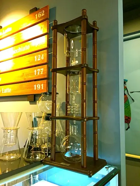 Hög kallbryggare med flera glaskärl i en träram på ett café.