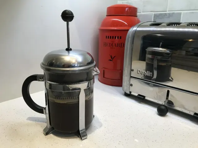 Kaffe drar i en Bodum-presskanna på en köksbänk.