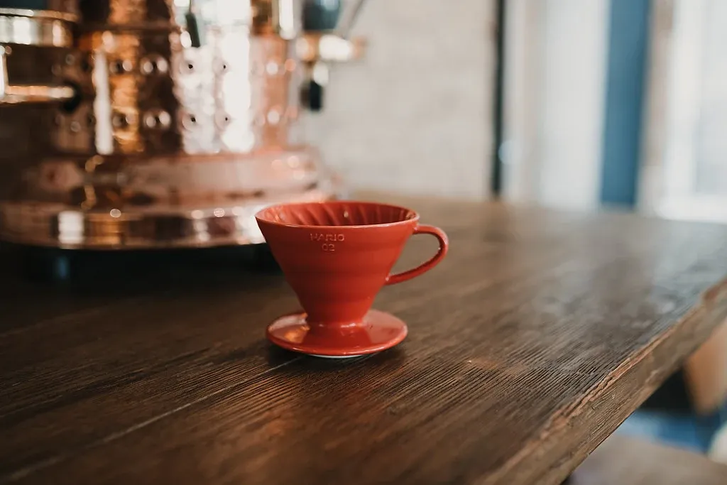 Röd Hario V60-handbryggare på en träbänk i ett café.