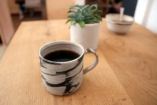 Mönstrad kaffemugg med handtag på ett träbord.