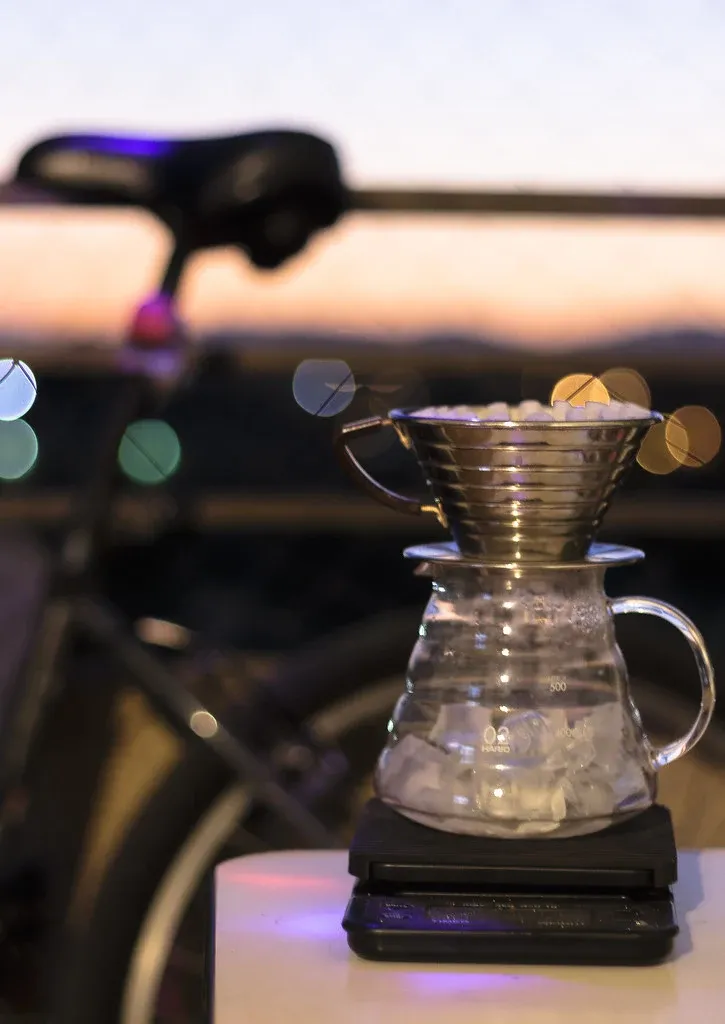 Kalita Wave med veckat filterpapper över en Hario-glaskanna med is, placerad på en våg.