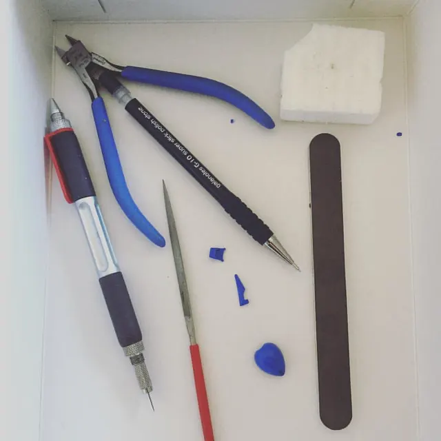 Ett litet modellbyggarkit med GodHand-avbitare, kniv, fil och slipmaterial. Fotografens exempel på verktyg för att bygga plastmodeller; innehållet är inte ett färdigpaketerat set.