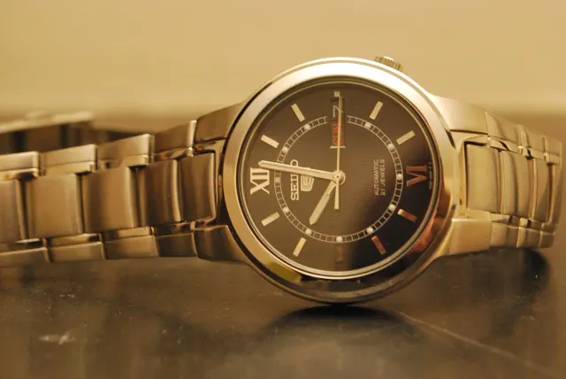 Seiko 5 SNKA23 med mörk urtavla och stållänk.