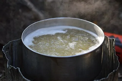 Pasta kokar i en metallkastrull på ett friluftskök