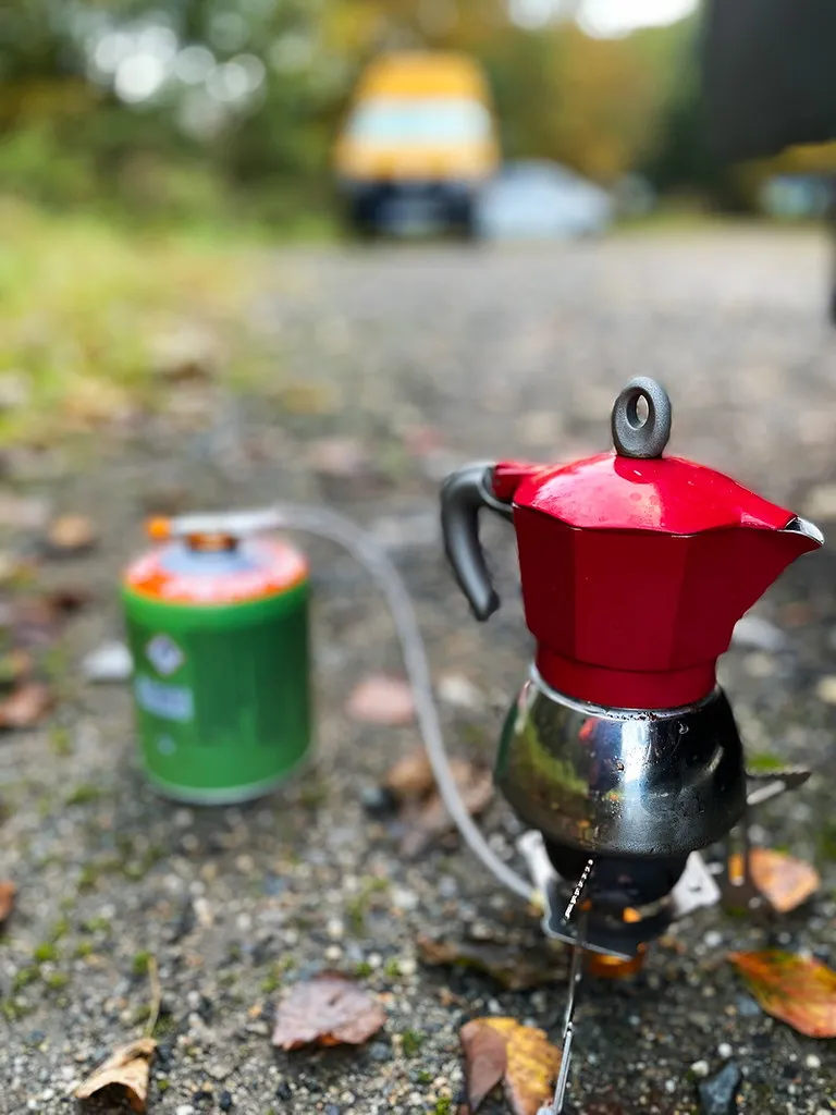 Röd mokabryggare på ett litet friluftskök med en mugg bredvid