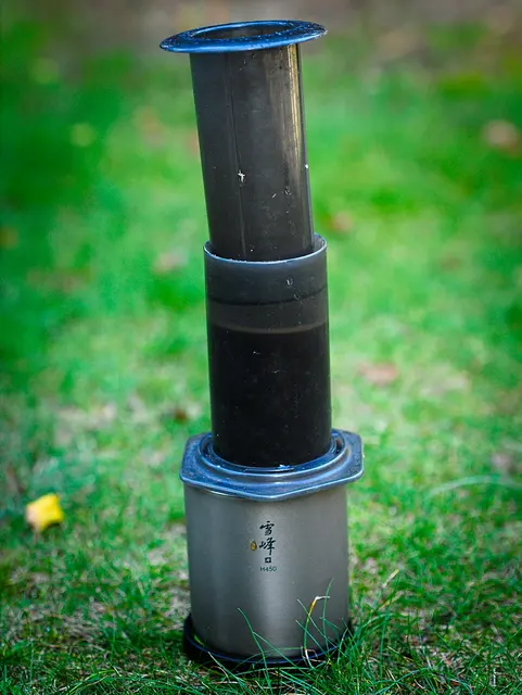 AeroPress ovanpå en Snow Peak-mugg i gräset