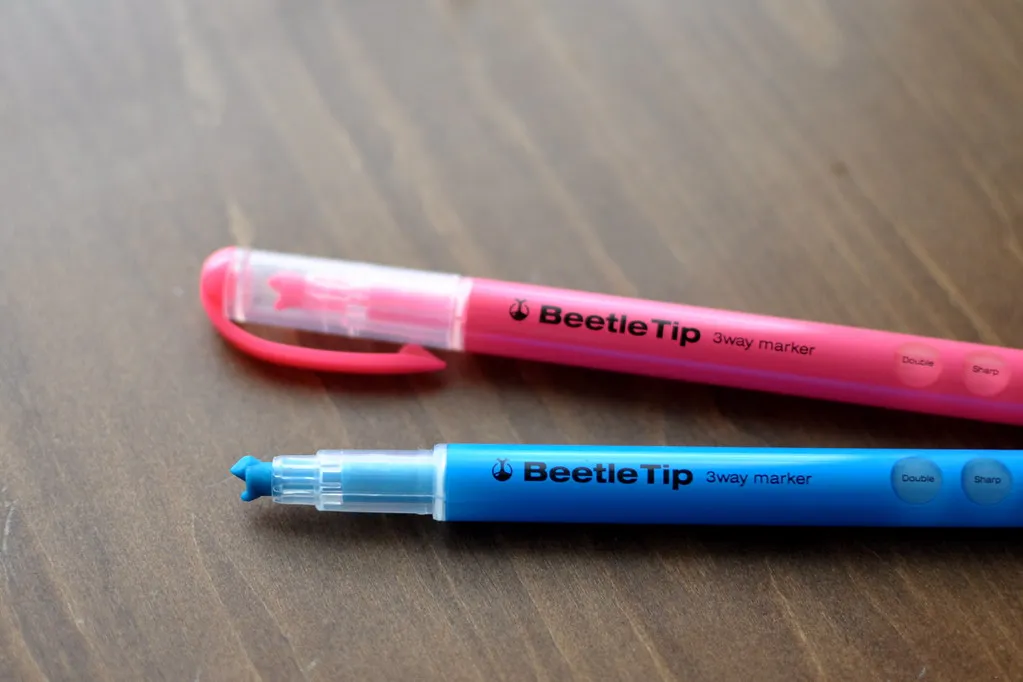 Två KOKUYO Beetle Tip-överstrykningspennor, en med spetsen synlig. Exempel på japansk spetsutformning för markeringsarbete.