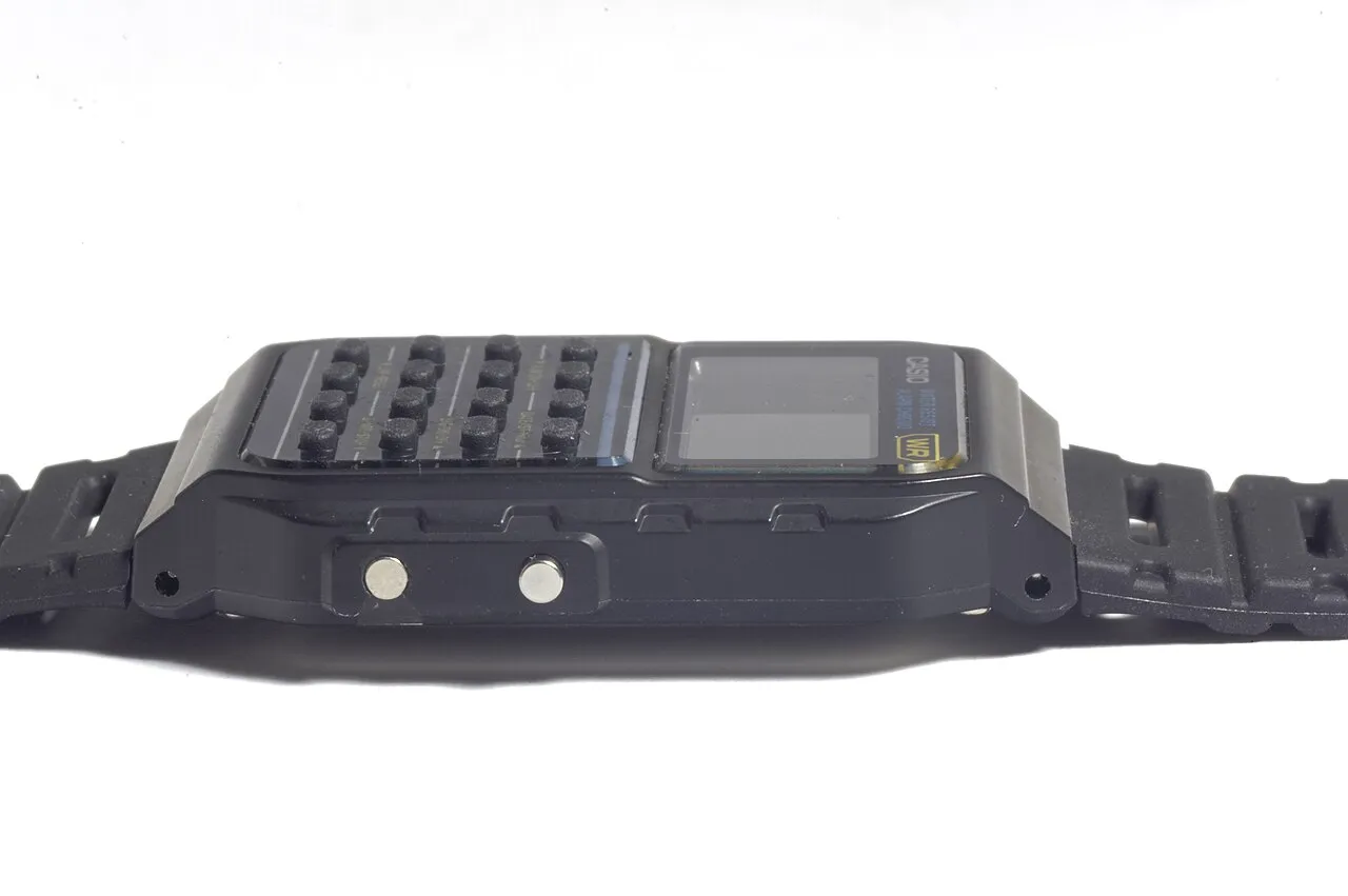 Casio CA-53W-1EZ – CA-53W-1EZ i sidoprofil med sidoknappar och bandinfästning synliga.
