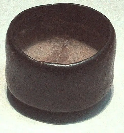 Eine schwarze Raku-Teeschale mit unregelmäßig wirkender Oberfläche.
