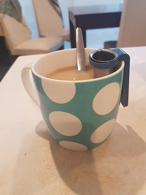 Gemusterter Teebecher mit einem Metallsieb.