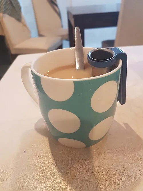Gemusterter Teebecher mit einem Metallsieb.