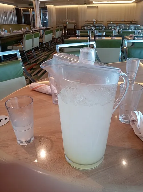 Limonadenkrug mit Trinkglas auf einem Tisch.