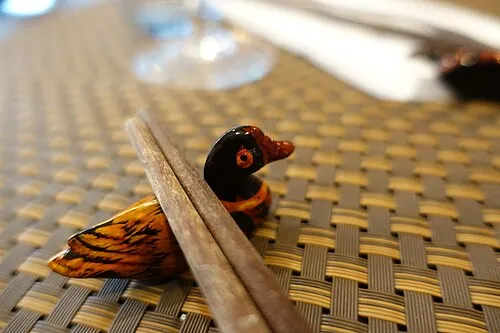 Hölzerne Essstäbchen auf einer bemalten Vogelablage.