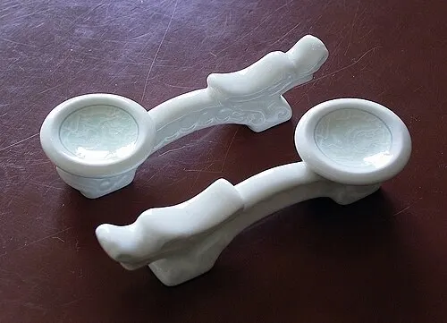 Zwei weiße Noritake-Stäbchenablagen in dekorativer Form.