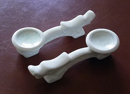 Zwei weiße Noritake-Stäbchenablagen in dekorativer Form.