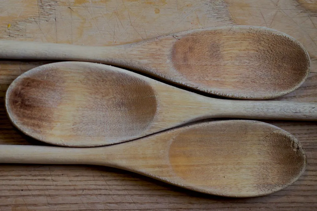 Drei benutzte Holzlöffel auf einem Holzbrett.