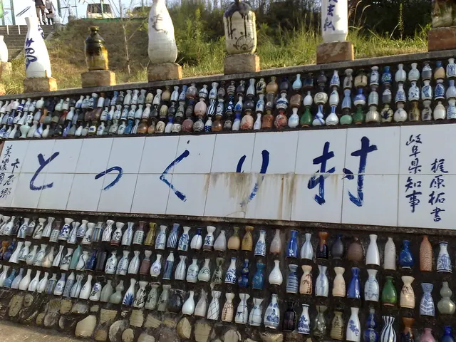 Mauer mit vielen eingelassenen kleinen Sake-Flaschen und großen Tokkuri darüber