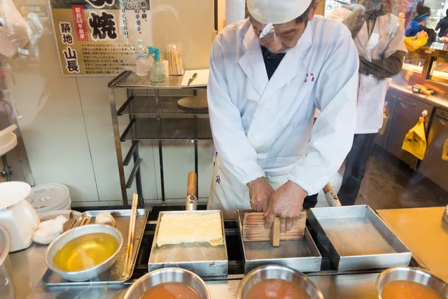 Koch am Tsukiji-Markt mit mehreren rechteckigen Tamagoyaki-Pfannen