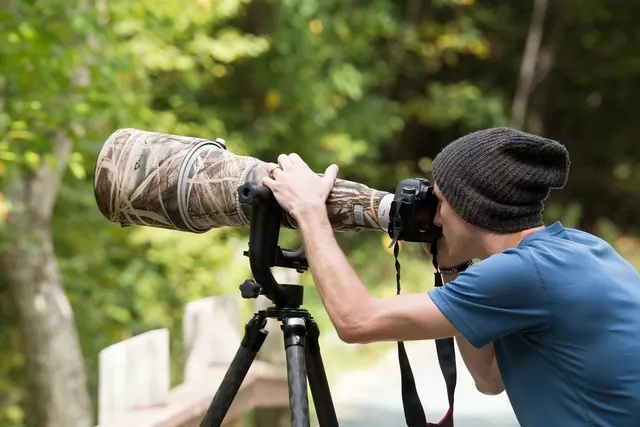 Fotograf mit großem Teleobjektiv auf einem Stativ im Freien