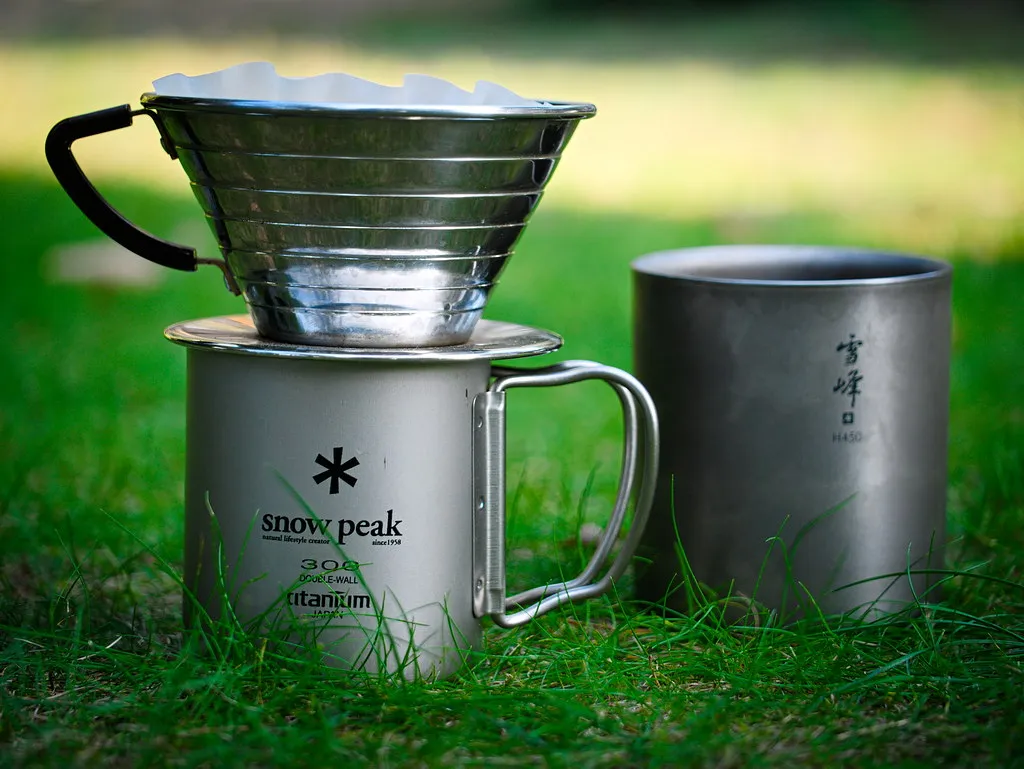 Metall-Kaffeefilter auf einem Snow-Peak-Becher neben einem zweiten Titanbecher