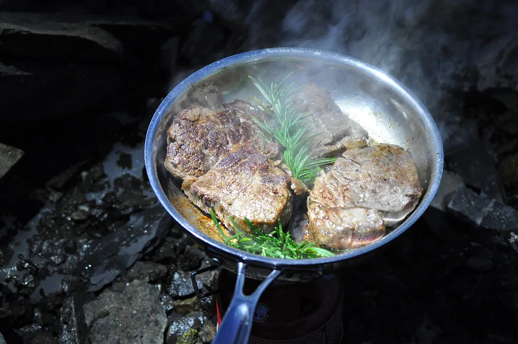 Pfanne mit Fleisch und Gemüse beim Kochen im Freien