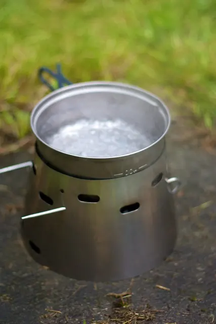 Metalltopf mit kochendem Wasser auf einem umschließenden Campingkocher