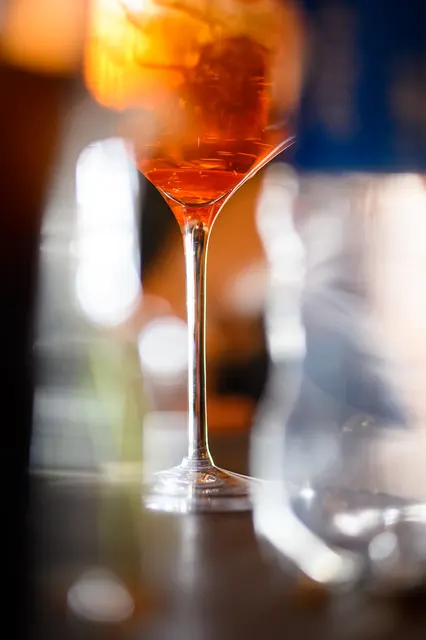 Schmales Glas auf einer Bar mit stark unscharfem Hintergrund