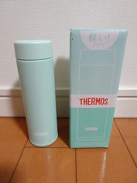 Mintfarbene Thermos-Flasche neben ihrer Originalverpackung