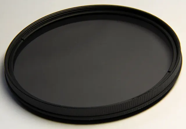 Nahaufnahme eines Polfilters mit dunkler Glasfläche und gerändelter Fassung