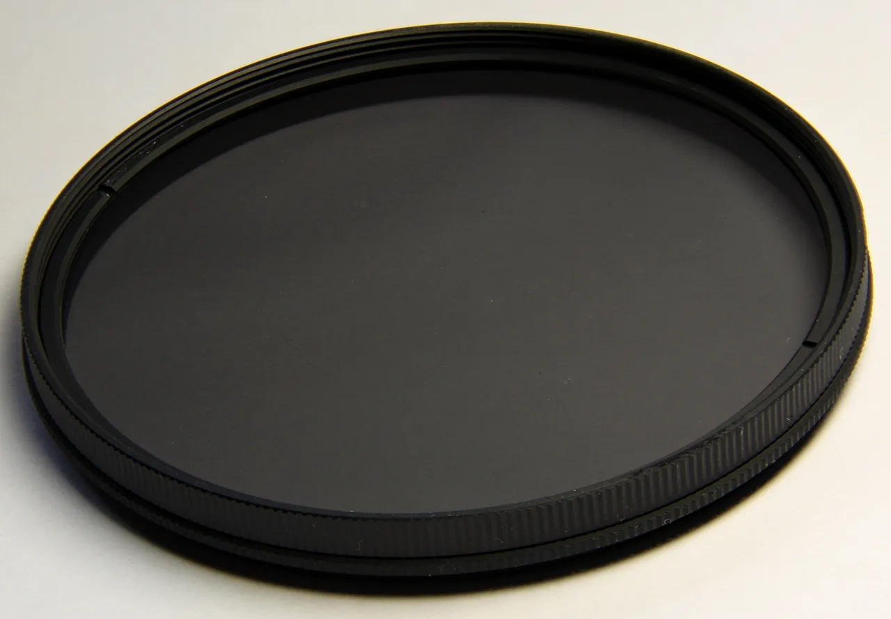 Nahaufnahme eines Polfilters mit dunkler Glasfläche und gerändelter Fassung
