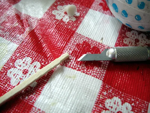 Klinge und gerändelter Griff eines Präzisionsmessers bei feiner Arbeit an einem Holzstäbchen.