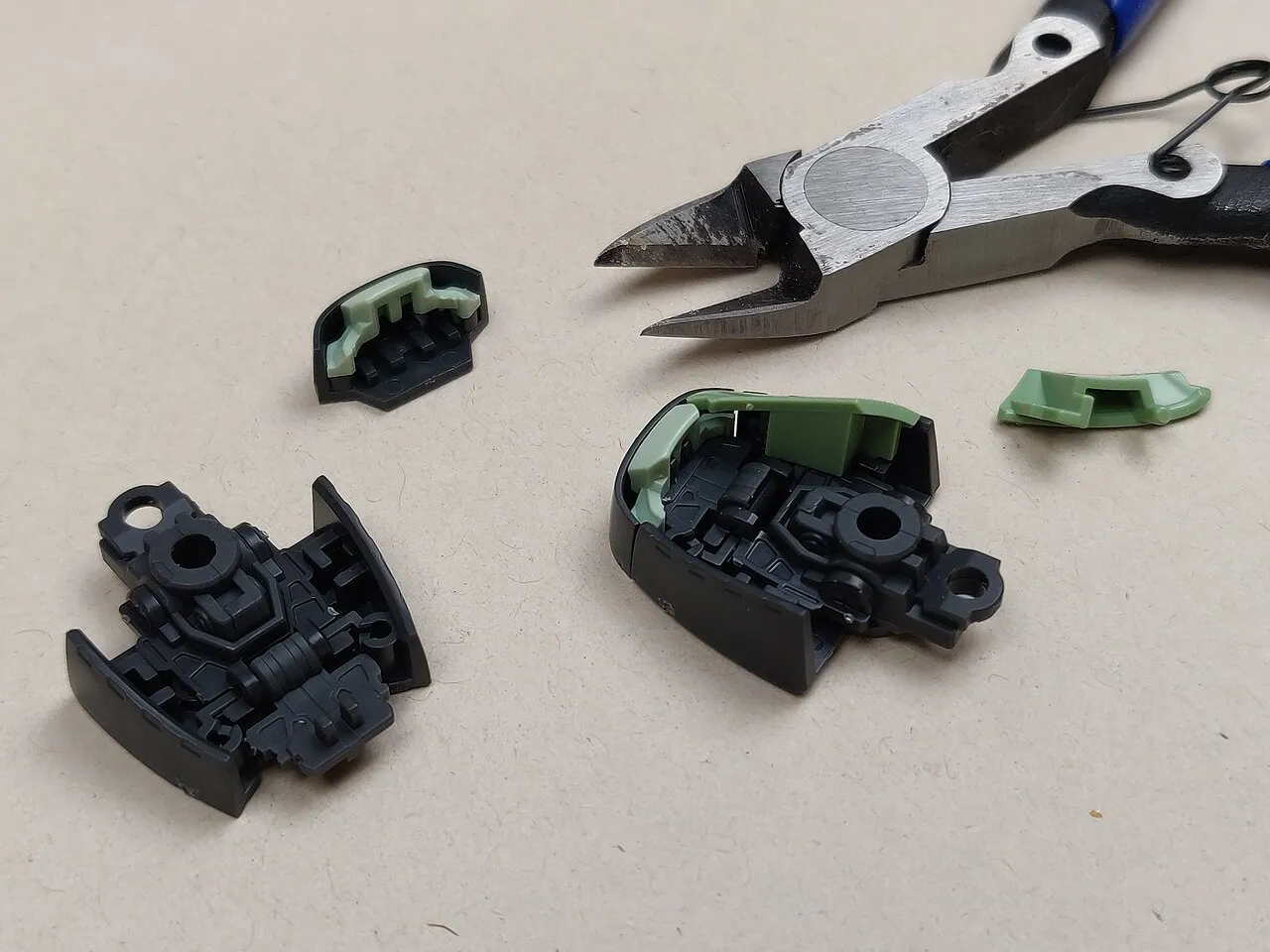 Kleine Gunpla-Bauteile neben einem feinen Seitenschneider; Kontextfoto für das kontrollierte Lösen und Montieren von Kunststoffteilen.