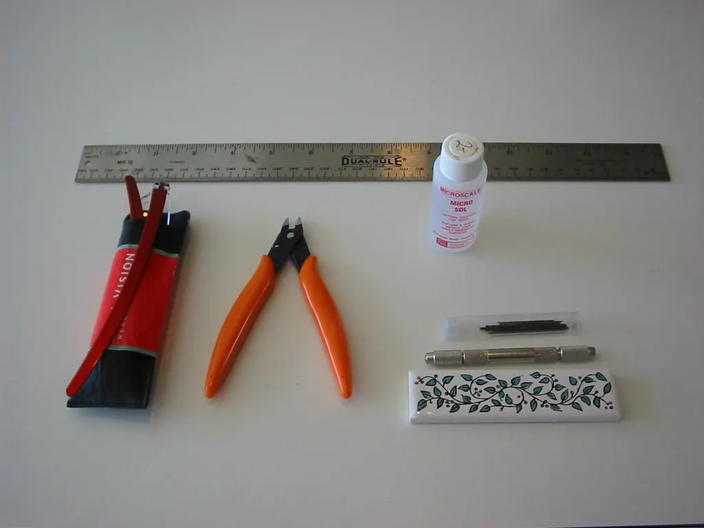 Modellbauwerkzeuge mit Handbohrer, kleinen Spiralbohrern, Seitenschneider und Lineal.