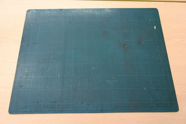 Gebrauchte gerasterte Schneidmatte mit sichtbaren Nutzungsspuren.