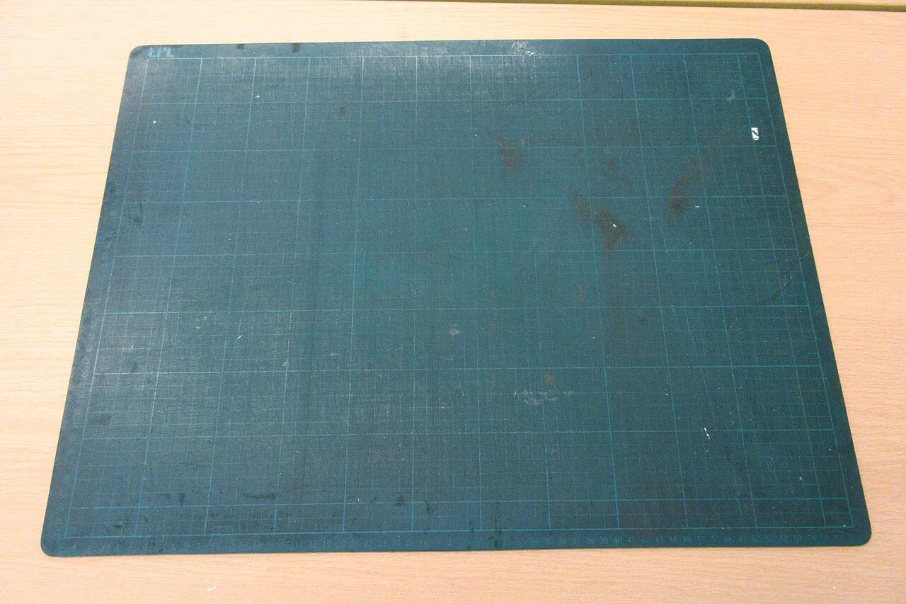Gebrauchte gerasterte Schneidmatte mit sichtbaren Nutzungsspuren.