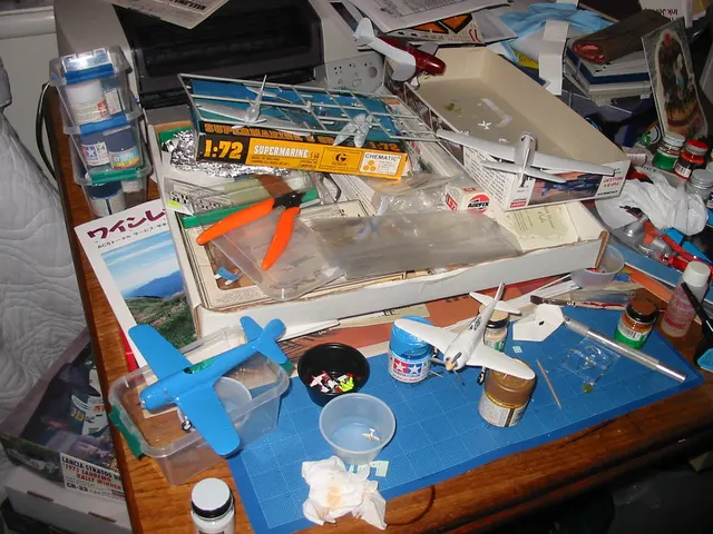 Modellbau-Arbeitsplatz mit Flugzeugbausätzen, Seitenschneider, Präzisionsmesser und Farbtöpfen. Kontextfoto für ein Werkzeuggeschenk, das zum vorhandenen Bausatz passen soll.