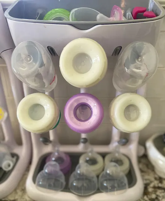 Trocknungsgestell mit Babyflaschen und einzelnen Verschlussteilen.