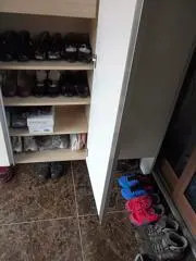 Schuhregal direkt neben einer Tür in einem schmalen Eingangsbereich.