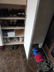 Schuhregal direkt neben einer Tür in einem schmalen Eingangsbereich.
