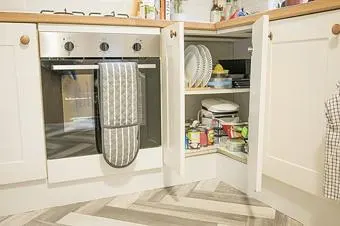 Geöffneter Küchenschrank mit Einlegeböden und abgestellten Vorräten. Kontextfoto zum Messen von Innenraum, Türöffnung und Zugriff.