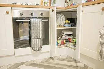 Geöffneter Küchenschrank mit Einlegeböden und abgestellten Vorräten. Kontextfoto zum Messen von Innenraum, Türöffnung und Zugriff.
