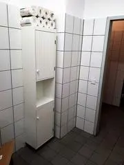 Schmaler Toilettenschrank mit Toilettenpapierrollen auf der oberen Fläche. Kontextfoto für Reserve und erreichbaren Stauraum.