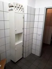 Schmaler Toilettenschrank mit Toilettenpapierrollen auf der oberen Fläche. Kontextfoto für Reserve und erreichbaren Stauraum.