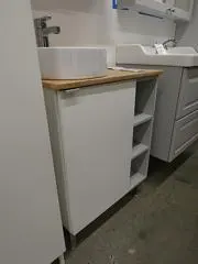Badmöbel mit geschlossener Tür und offenem Seitenfach in einer IKEA-Ausstellung. Kontextfoto für unterschiedliche Zugriffsarten.