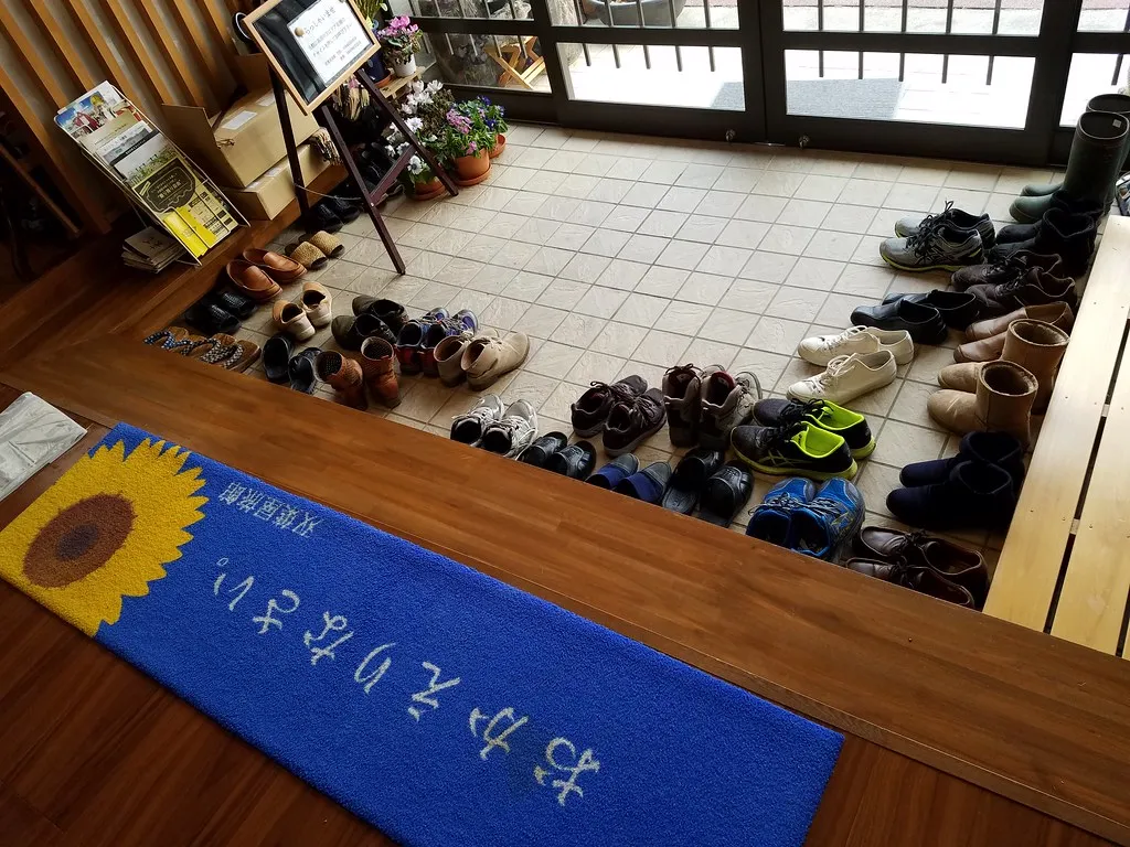 Schuhe am Rand eines japanischen Eingangsbereichs. Kontextfoto zum Freihalten des Durchgangs.